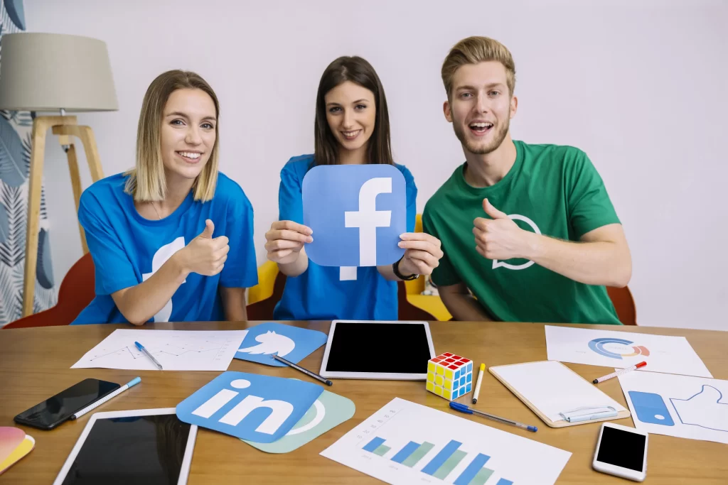 smiling woman holding facebook logo with his friends showing thumbup sign min scaled
